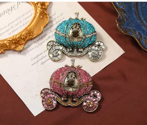 Macro-opname van twee vintage strass-steentjes pompoenkoets broches op een getextureerde kaart.