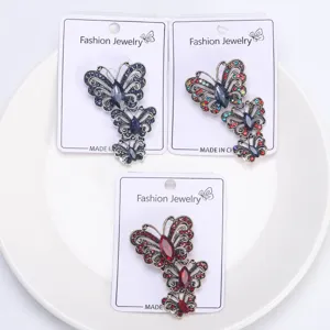 Primer plano de tres broches de mariposa de cristal vintage en azul, rojo y multicolor