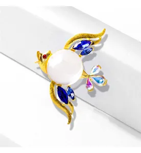 Detailed macro shot of a bird-shaped brooch with blue crystals and a large white pearl