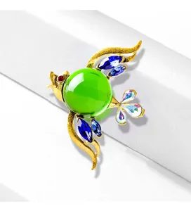 Close-up of bird brooch with green jelly glass belly and blue crystal wings