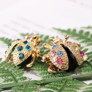 Detailed macro shot of cute colorful rhinestone ladybug brooches on a green leaf