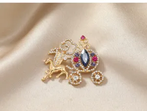 Macro view of a golden fairy tale pumpkin carriage brooch with colorful rhinestones on silk