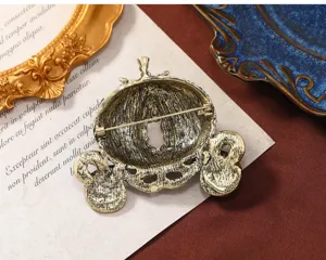 Gedetailleerd achteraanzicht van een gouden vintage pompoenwagenbroche met speld.