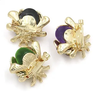 Detail view of the back of cartoon beetle brooches with golden safety pin clasps