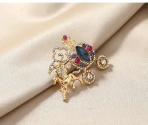 Close-up of gold Cinderella pumpkin carriage brooch with multi-color rhinestones