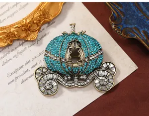 Detailopname van een luxe vintage pompoenwagenbroche met blauwgroene strassteentjes.