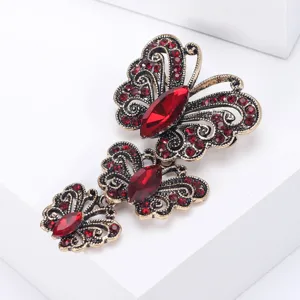 Primer plano de un broche vintage de tres mariposas con cristales rojos y acabado dorado