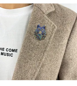 Detail view of a vintage wolf head brooch with colorful blue and teal rhinestones on a blazer
