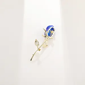 Eleganter blau-goldener Rosen-Brosche mit funkelnden Blättern auf weißem Hintergrund