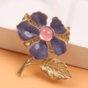Detailed view of a purple cherry blossom brooch with a pink cat-eye stone and gold leaf.
