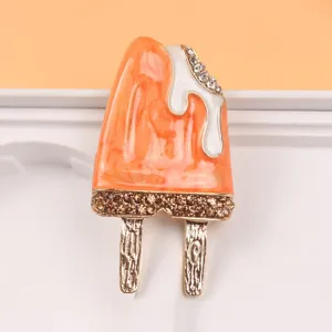 Close-up detail view of orange enamel popsicle brooch with rhinestone embellishments.