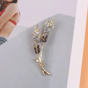 Gedetailleerde macro-opname van een elegante gouden tarwebroche met blauwe kristallen