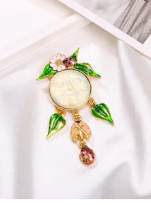 Gros plan détaillé d'une broche vintage en émail avec visage de lune et breloques scarabée