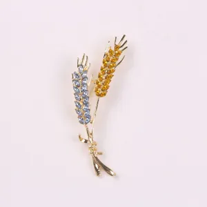 Close-up van een gouden tarwebroche met glinsterende blauwe en amberkleurige kristallen
