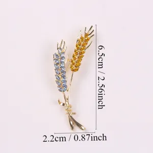 Gedetailleerd overzicht van de gouden tarwebroche met blauwe en gele strass, 6,5 x 2,2 cm