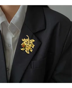 Detailed view of a vintage gold maple leaf brooch pinned to a professional black blazer