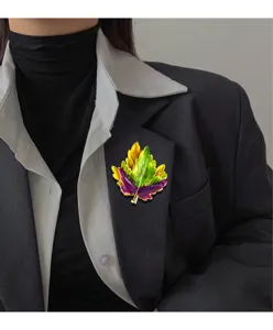 Close-up detail of a vibrant enamel maple leaf brooch on a dark blazer jacket lapel.