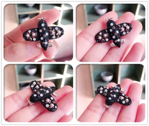 Collage mit vier Ansichten einer funkelnden schwarzen Flugzeugbrosche mit Strass und Sternen.