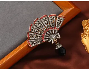 Gedetailleerd overzicht van een vintage Chinese waaierbroche met rode strass-steen