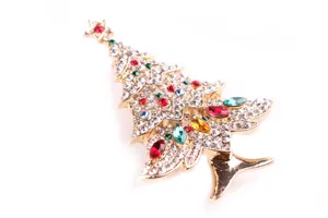 Close-up detail of a glittering Christmas tree brooch with colorful rhinestones on white