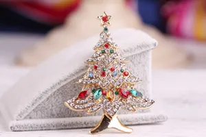 Detailed macro view of a gold-toned Christmas tree brooch with colorful rhinestones.