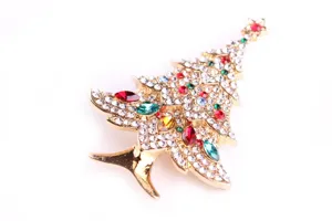 Close-up of a sparkling Christmas tree brooch with colorful rhinestones on gold alloy.