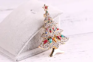 Detailed close-up of a sparkling Christmas tree brooch with multi-colored rhinestones.