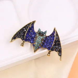 Detailed view of a vintage gold-toned bat brooch with blue and black rhinestones