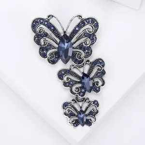 Macro de tres elegantes broches de mariposa vintage con cristales azules sobre blanco