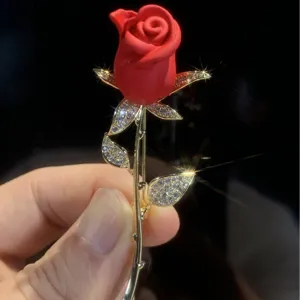 Eleganter roter Rosenanstecker mit funkelnden Kristallen und goldenem Stiel als Geschenk