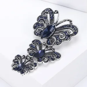 Detalle de un broche de mariposa de plata vintage con cristales de color azul oscuro.