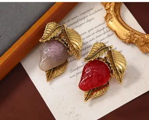 Primer plano de broches de fresa de resina vintage con hojas doradas en fondo cálido