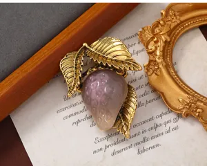 Vista detallada de un broche de fresa en resina gris con hojas doradas estilo vintage