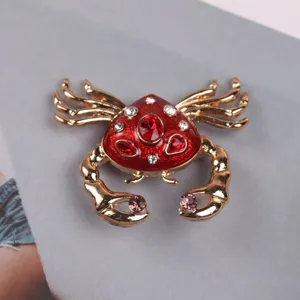 Detailed close-up showing the red enamel shell and crystal accents of the crab brooch.