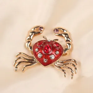 Close-up of a gold-toned crab brooch with red enamel and sparkling rhinestones