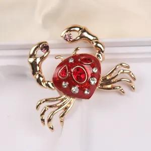 Detailed view of gold-tone crab brooch with red enamel and sparkling rhinestones