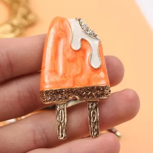 Detailed view of a cute orange enamel popsicle brooch adorned with sparkling rhinestones