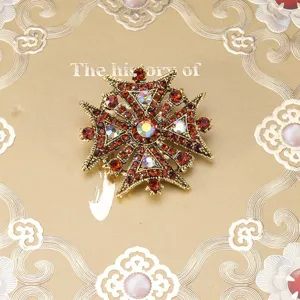 Vintage baroque style cross brooch adorned with red and iridescent rhinestones in gold