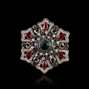 Broche vintage barroco con gema central verde esmeralda y cristales rojos marquise