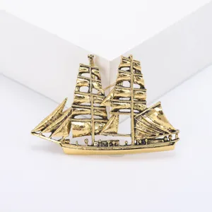 Detailopname van een vintage gouden zeilschipbroche met ingewikkelde masten en zeilen