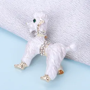 Détail d'une broche caniche en émail blanc avec colliers en strass et accents dorés.