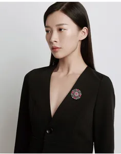 Close-up of vintage Baroque palace style brooch with red and white gems on black blazer.
