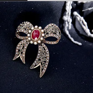 Elegant vintage bow brooch featuring red faceted stone and white pearls for women