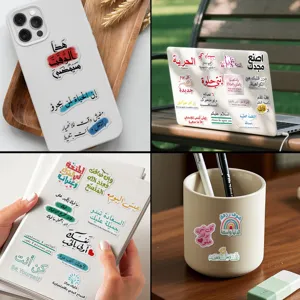Detailed view of assorted Arabic motivational stickers applied on laptop and phone case.