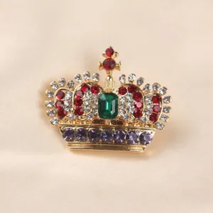 Detailed view of vintage gold crown brooch set with emerald green and multicolor crystals
