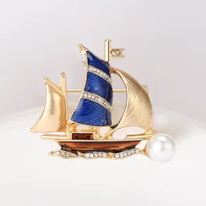 Close-up detail of an elegant sailboat brooch with blue enamel sails and a white pearl