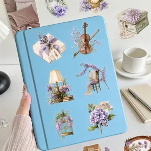 Adesivi in PET con fiori viola vintage che decorano la copertina di un taccuino azzurro