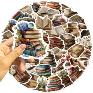Hand holding a vintage book sticker featuring blue flowers and a crystal ball detail