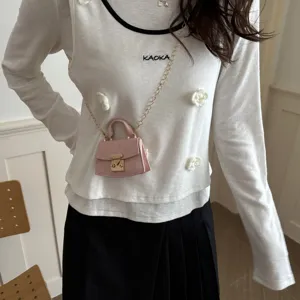 Detailed shot of a stylish miniature pink crossbody accessory bag with gold chain strap