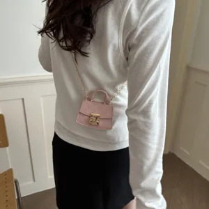 Detailed view of a trendy mini pink crossbody accessory bag with gold chain strap